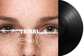 Vinyl album cover for Tribal Soul by Carlos Simpson, released on December 19, 2020, under Carlos Simpson Music Production. The artwork features a close-up of a freckled face with expressive brown eyes, crossed horizontally by a white line. The album title "TRIBAL Soul" appears layered across the eyes, blending bold and handwritten typography, reflecting themes of identity, humanity, and emotion.