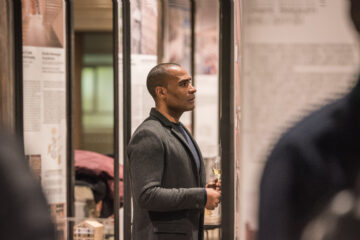 Carlos Simpson, founder of Carlos Simpson Design Studio, photographed at a creative industry exhibition in London — reflective moment capturing his role as an artist, designer, and thought leader in branding, typography, and contemporary visual culture.