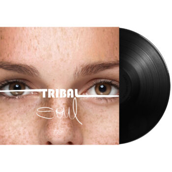 Vinyl album cover for Tribal Soul by Carlos Simpson, released on December 19, 2020, under Carlos Simpson Music Production™. The artwork features a close-up of a freckled face with expressive brown eyes, crossed horizontally by a white line. The album title “TRIBAL Soul” appears layered across the eyes, blending bold and handwritten typography, reflecting themes of identity, humanity, and emotion.