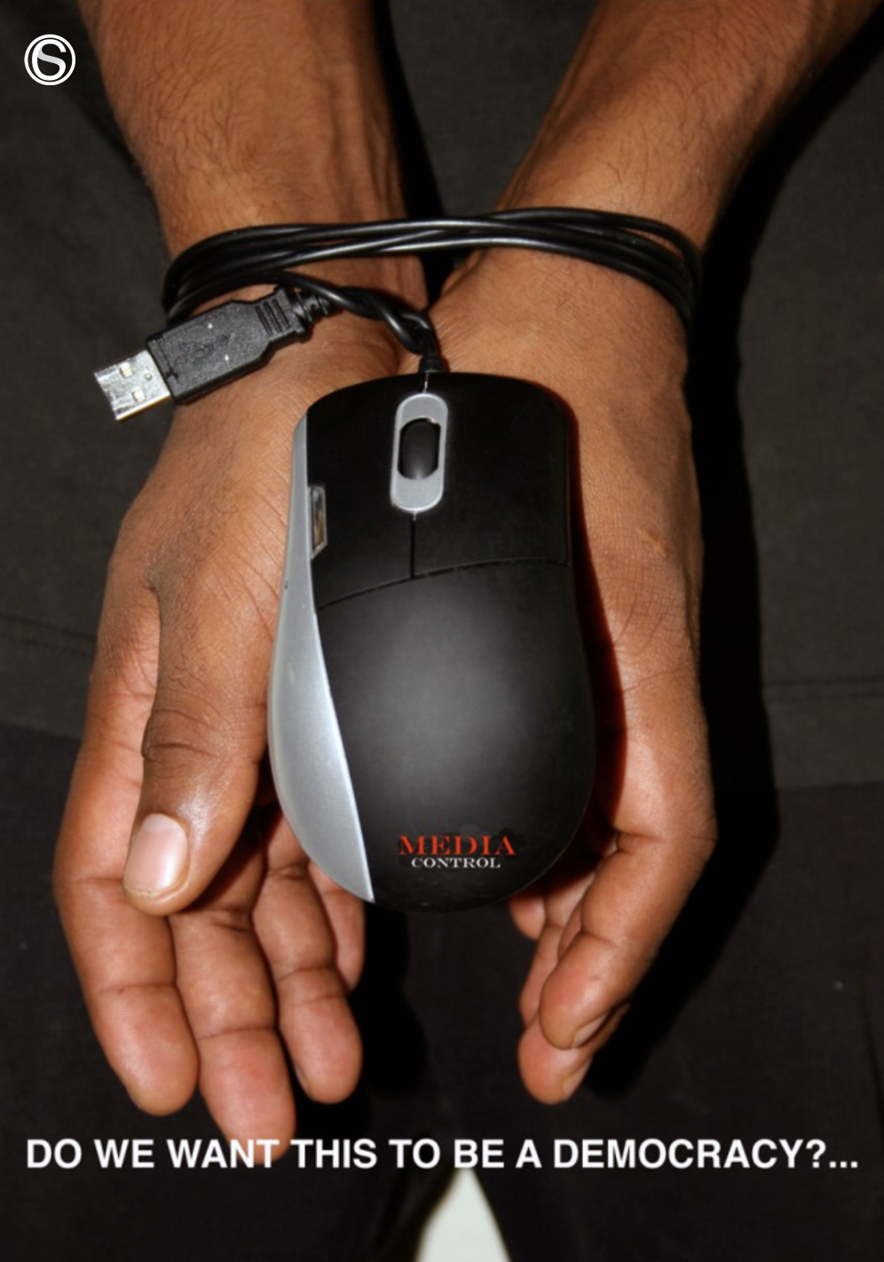 Hands bound with a computer mouse cable symbolizing loss of freedom through media control and digital surveillance, with the question "Do we want this to be a democracy?