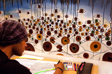 Carlos Simpson seated in profile during a reflective drawing session, focused on mark-making and creative process.