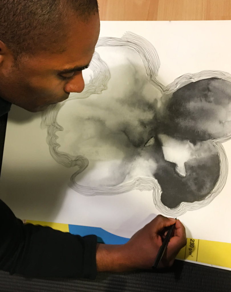 Carlos Simpson seated in profile during a reflective drawing session, focused on mark-making and creative process.